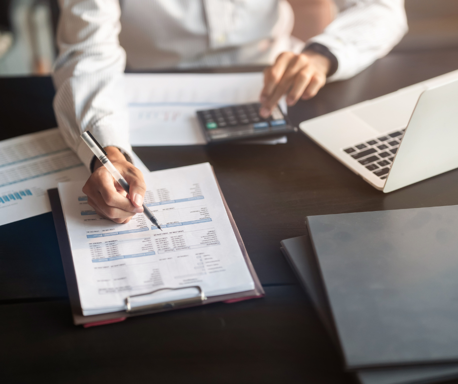 Person prüft Finanzunterlagen mit Taschenrechner und Laptop