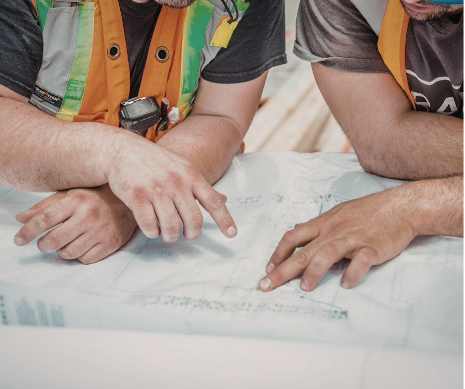Zwei Bauarbeiter besprechen einen Bauplan auf der Baustelle